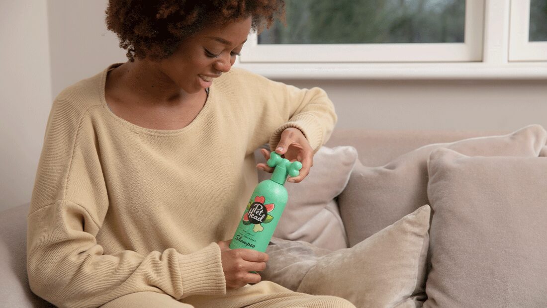 lady smiling with applying furtastic spray to her Terrier
