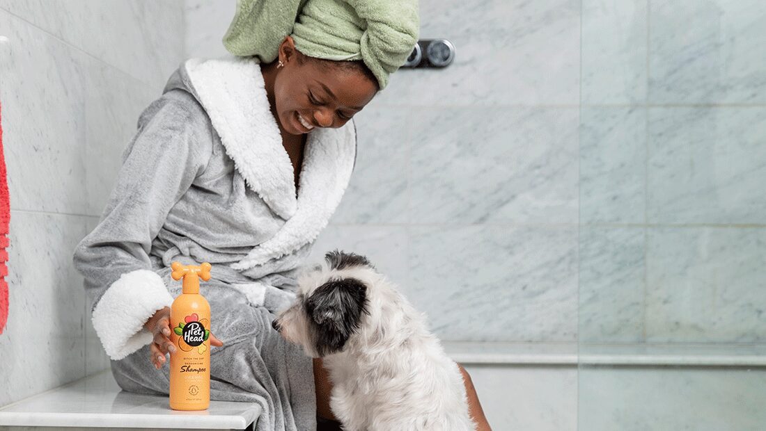 lady smiling at her dog after her shower with Ditch the Dirt shampoo in foreground